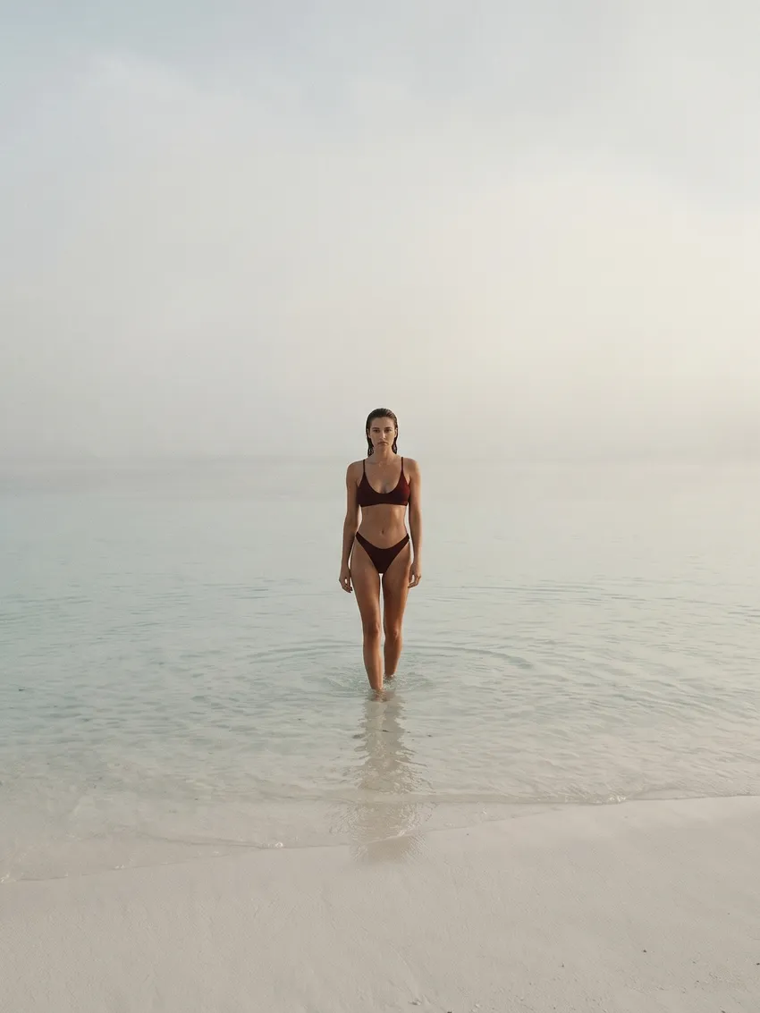 Femme en maillot Pampelonne grenat sortant de la mer au petit matin.